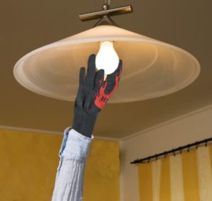 hand in glove changing hot light bulb